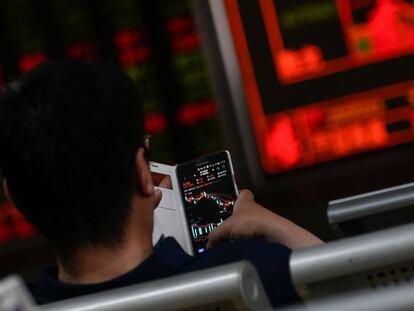 Un inversor mira los movimientos del mercado en Pekín el 14 de mayo de 2019. En vídeo, declaraciones del ministro de Relaciones Exteriores de China, Wang Yi.
