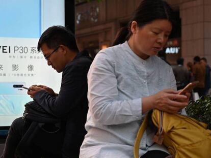 Usuarios con móviles junto a un anuncio de Huawei en Shanghái. En vídeo, Trump da un paso más en su guerra comercial con China.