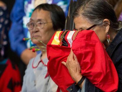 Una anciana indígena canadiense sostiene una copia del informe final sobre el genocidio que ha sufrido su pueblo, el tres de junio en Quebec. En vídeo, el primer ministro canadiense, Justin Trudeau, reconoce el genocidio, el pasado tres de junio.