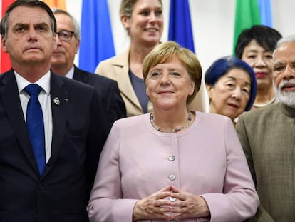 Angela Merkel (centro), en un evento durante la cumbre del G20 en Osaka, este sábado. En vídeo, Merkel sufre temblores durante un acto oficial el pasado jueves en Berlín.