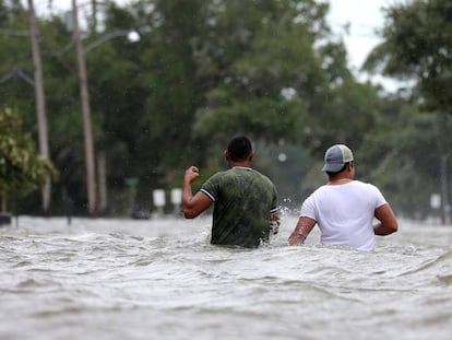 Dos hombres caminan en una calle inundada en la ciudad de Mandeville, Luisiana.