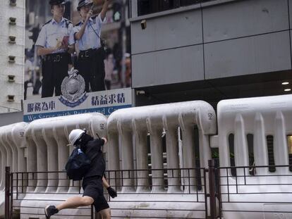 Un manifestante tira piedras a la comisaría de policía en Tseung Kwan. En vídeo, imágenes de las protestas de este sábado.