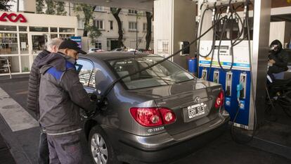 Un empleado ayuda a un cliente a repostar en una gasolinera de Buenos Aires. En vídeo, declaraciones del Presidente de Argentina, Mauricio Macri y del candidato a la presidencia, Alberto Fernández.