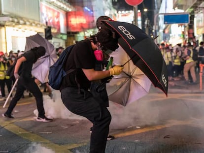 Manifestantes intentan protegerse de los gases lacrimógenos lanzados por la policía, este domingo en Hong Kong. En vídeo, imágenes de las protestas.