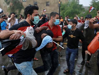 Dos hombres transportan a un herido en medio de una protesta en Bagdad, este viernes. En vídeo, imagenes de las protestas.