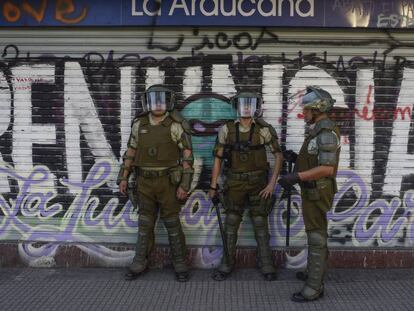 Policías chilenos custodian el sábado un supermercado cerrado por las protestas en Santiago. En vídeo, las declaraciones del ministro del Interior chileno anunciando su plan para hacer una nueva constitución.