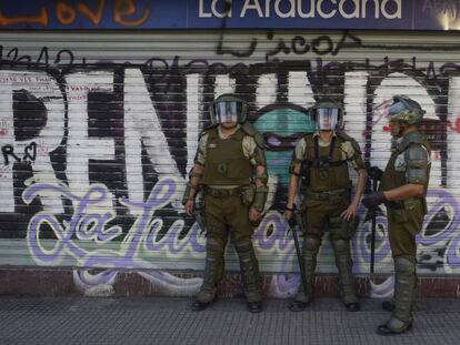 Policías chilenos custodian el sábado un supermercado cerrado por las protestas en Santiago. En vídeo, las declaraciones del ministro del Interior chileno anunciando su plan para hacer una nueva constitución.