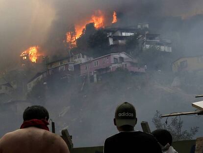 Varios hombres contemplan el incendio en el cerro Rocuant, de Valparaíso, en la noche del martes.