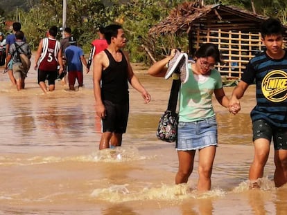 Un grupo de personas atraviesa una carretera inundada este jueves en Ormoc (Filipinas). En vídeo, imágenes del tifón Phanfone a su paso por el país del sudeste asiático.