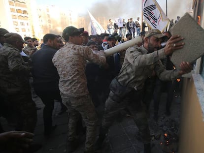 Un grupo de manifestantes atacan la Embajada de Estados Unidos en Bagdad, este martes. En vídeo, el presidente de Estados Unidos, Donald Trump, ofrece declaraciones a los medios sobre la situación en Irak.