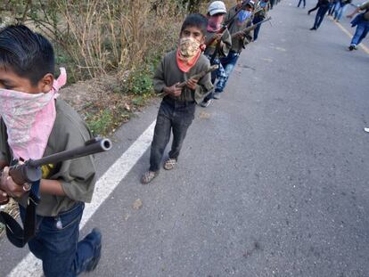 Un menor de edad cargando un rifle en Chilapa, Guerrero. En vídeo, menores de edad marchando.