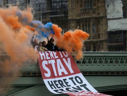 Un grupo de personas sostiene bengalas de humo mientras coloca una pancarta en el puente de Westminster, en Londres, este viernes. En vídeo, tres españoles residentes en Londres expresan sus sentimientos sobre la salida del Reino Unido de la Unión Europea.