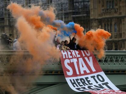 Un grupo de personas sostiene bengalas de humo mientras coloca una pancarta en el puente de Westminster, en Londres, este viernes. En vídeo, tres españoles residentes en Londres expresan sus sentimientos sobre la salida del Reino Unido de la Unión Europea.