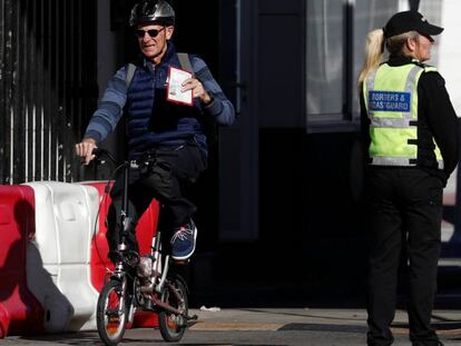 Un hombre cruza a Gibraltar subido en una bicicleta y muestra su pasaporte, este sábado.