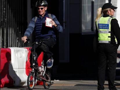 Un hombre cruza a Gibraltar subido en una bicicleta y muestra su pasaporte, este sábado.