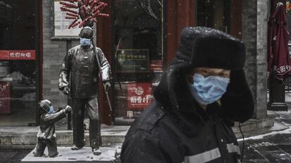 En foto, un hombre con mascarilla en una calle de Pekín con los establecimientos cerrados, el miércoles. En vídeo, China confirma la muerte por coronavirus del doctor Li Wenliang.