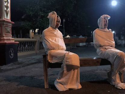 Dos voluntarios ataviados con disfraces de fantasmas amortajados en Kepuh (Indonesia). En vídeo, Indonesia saca fantasmas a las calles para que los vecinos no rompan la cuarentena.