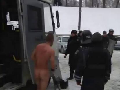 Un hombre desnudo, supuestamente un manifestante detenido, cerca de un autobus policial en Kiev.