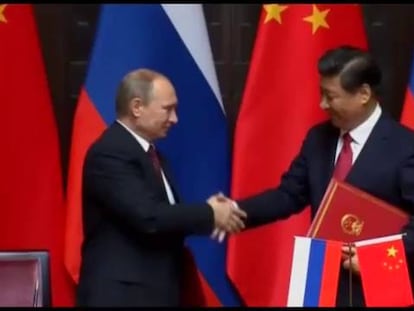 Vladímir Putin da a mão para Xi Jinping, nesta terça-feira em Xangai.