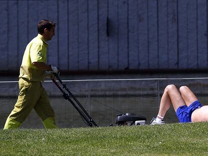 Un joven lee un libro mientras toma el sol en Madrid Río.