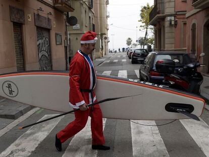 Un hombre disfrazado de Papa Noel por una calle de Barcelona.
