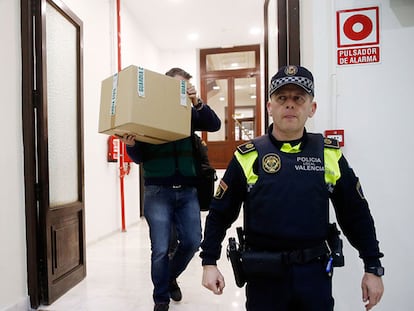 Un agente lleva una caja de las oficinas del PP en Valencia el martes. EFE