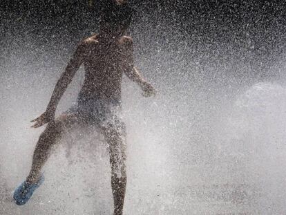 Un niño se divierte con el agua de una fuente de Pamplona.