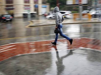 Un joven corre bajo la lluvia en Valencia.