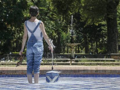 Una chica se refresca del intenso calor en una fuente del parque de Maria Luisa de Sevilla.