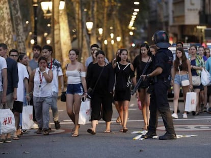 Un grupo de gente se desplaza entre el despliegue policial en el lugar del atentado, en las Ramblas de Barcelona.