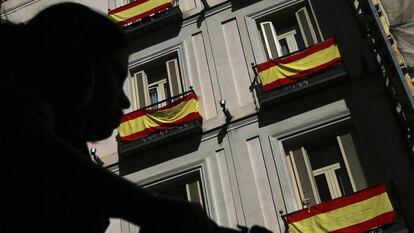 Un ciclista pasa por delante de banderas españolas en Madrid.