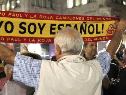 Un hombre sostiene una bandera con el lema "Yo soy español" ante el cartel colgado en el Ayuntamiento de Barcelona.