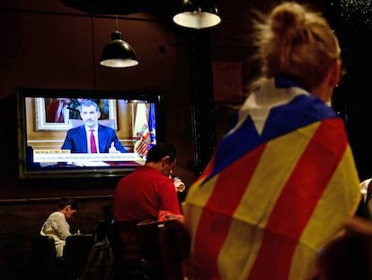 Una mujer envuelta en una bandera independentista sigue el discurso del Rey.