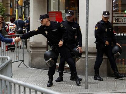 Un ciudadano saluda a un agente de la Policía Nacional que custodía la Jefatura Superior de Barcelona.