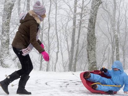 Una mujer con un niño juegan en la nieve en O Cebreiro (Lugo), donde ha caído una copiosa nevada.
