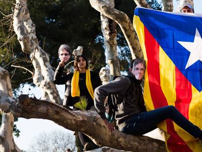 Manifestantes protestan frente a las puertas del Parlament llevando máscaras con la cara de Puigdemont.