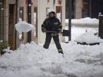 Un bombero retira la nieve en una calle de la localidad cántabra de Reinosa.