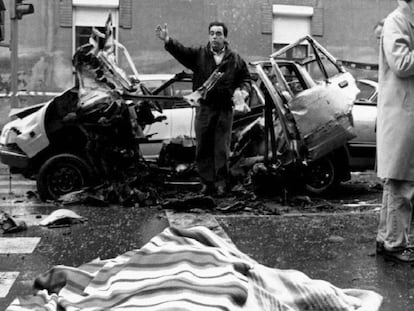 El cadáver del comandante Cortizo, cubierto por una manta, junto al coche destrozado por la bomba lapa.