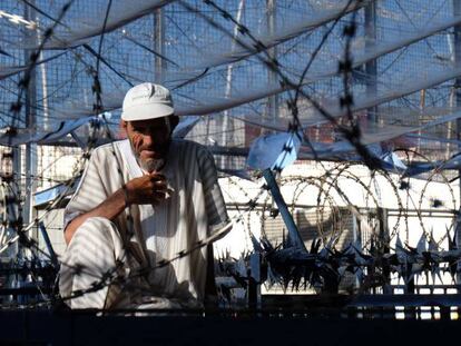 Un hombre descansa entre concertinas en la valla de la frontera entre España y Marruecos en Melilla. En vídeo: Los retos pendientes de la inmigración en Melilla