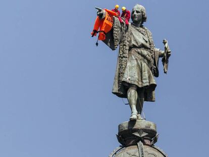 Activistas de ProActiva Open Arms cuelgan en la estatua de Colon un chaleco salvavidas. En vídeo, imágenes de la llegada del barco de Proactiva al puerto de Barcelona.