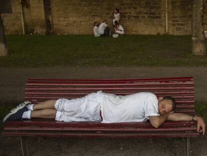 Un hombre duerme en un banco de Pamplona durante el primer día de San Fermín. En vídeo, 24 horas en los sanfermines