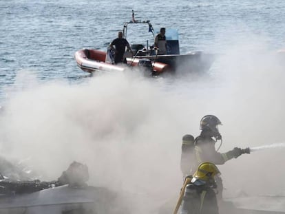 Los bomberos y equipos de rescate traban en la zona donde se incendió el catamarán en O Grove.