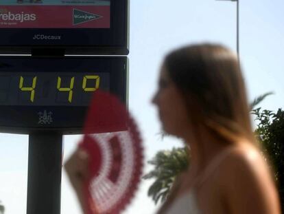 Una joven se abanica ante un termómetro que marca 44ºC este jueves en Córdoba. En vídeo, declaraciones de la gente sobre la ola de calor.