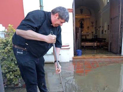 El párraco Eduardo Romero limpia los destrozos de las inundaciones.