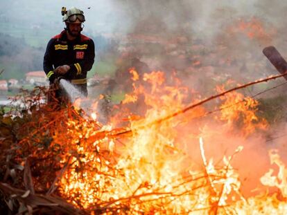 Un bombero trata de extinguir un incendio este lunes en Puente Viesgo (Cantabria). En vídeo, pillan a un pirómano in fraganti en Asturias.