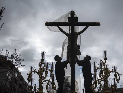 Dos costaleros cubren el 'Cristo de los favores' para protegerlo de la lluvia el pasado año en Granada. En vídeo, el miércoles llega un frente que traerá lluvias generalizadas.