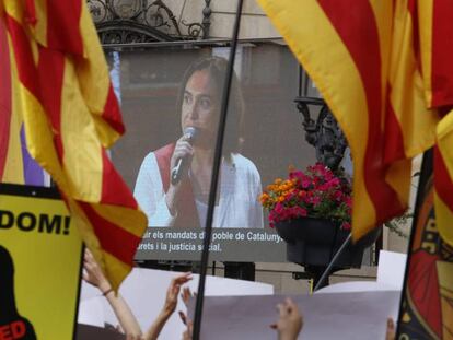 Ada Colau, en una pantalla instalada en la plaza de Sant Jaume, en Barcelona. En el vídeo, pleno de investidura.