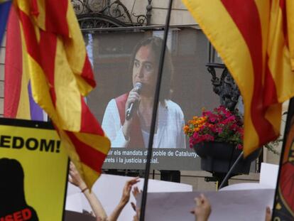 Ada Colau, en una pantalla instalada en la plaza de Sant Jaume, en Barcelona. En el vídeo, pleno de investidura.