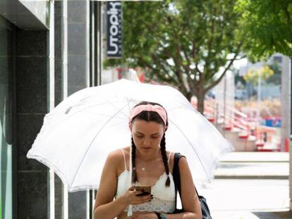 Una mujer pasea protegida por un paraguas en Lleida. En vídeo, la ola de calor se disipa pero Zaragoza continuará registrando altas temperaturas.