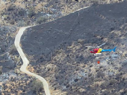 Vista desde la Cruz de Tejeda en la mañana de este lunes de un helicóptero en la zona arrasada por el incendio de Gran Canaria.